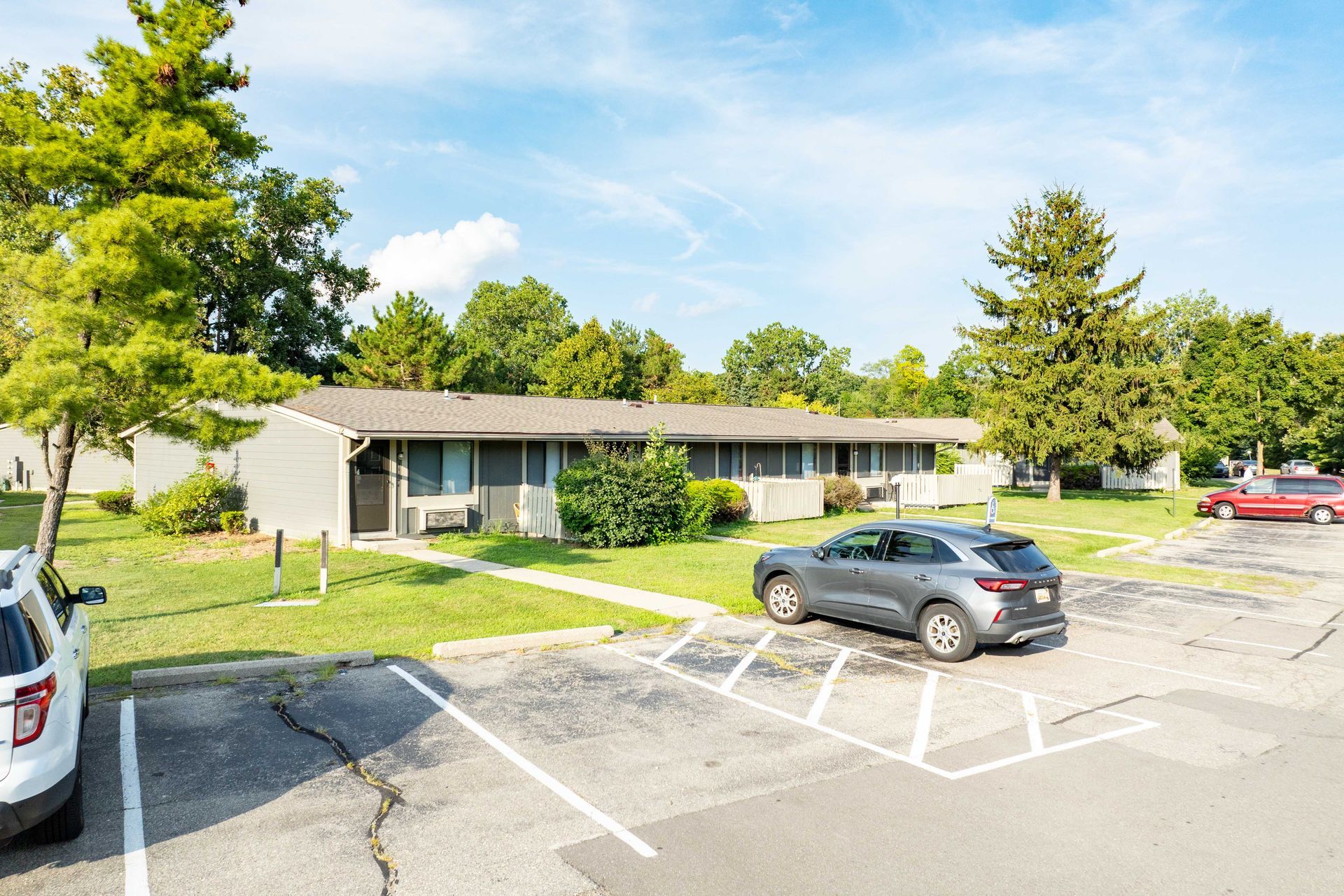 Apartment building with a car parked in front on a sunny day.
