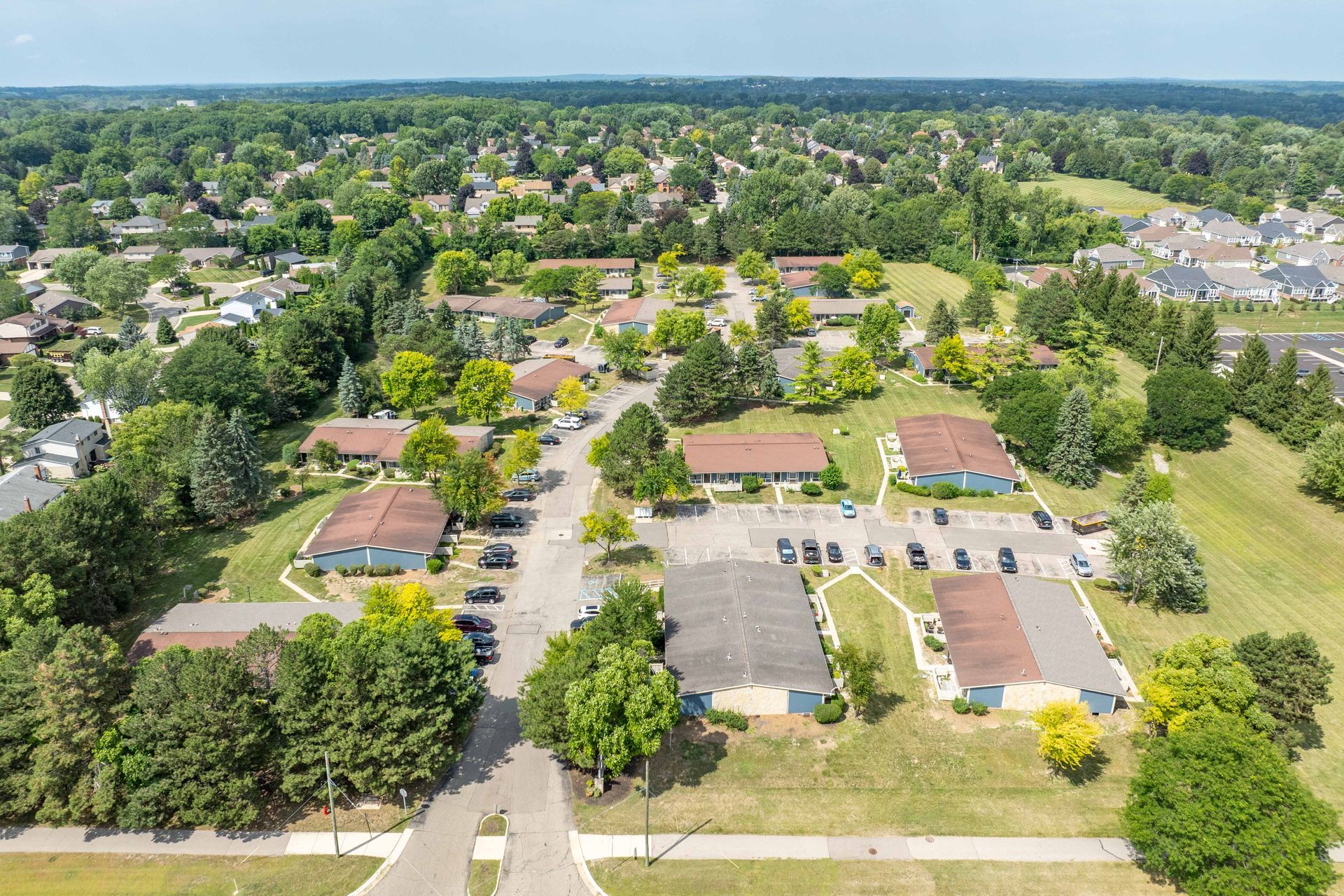 Aerial view of a residential neighborhood with houses, trees, parking lots, and green lawns.