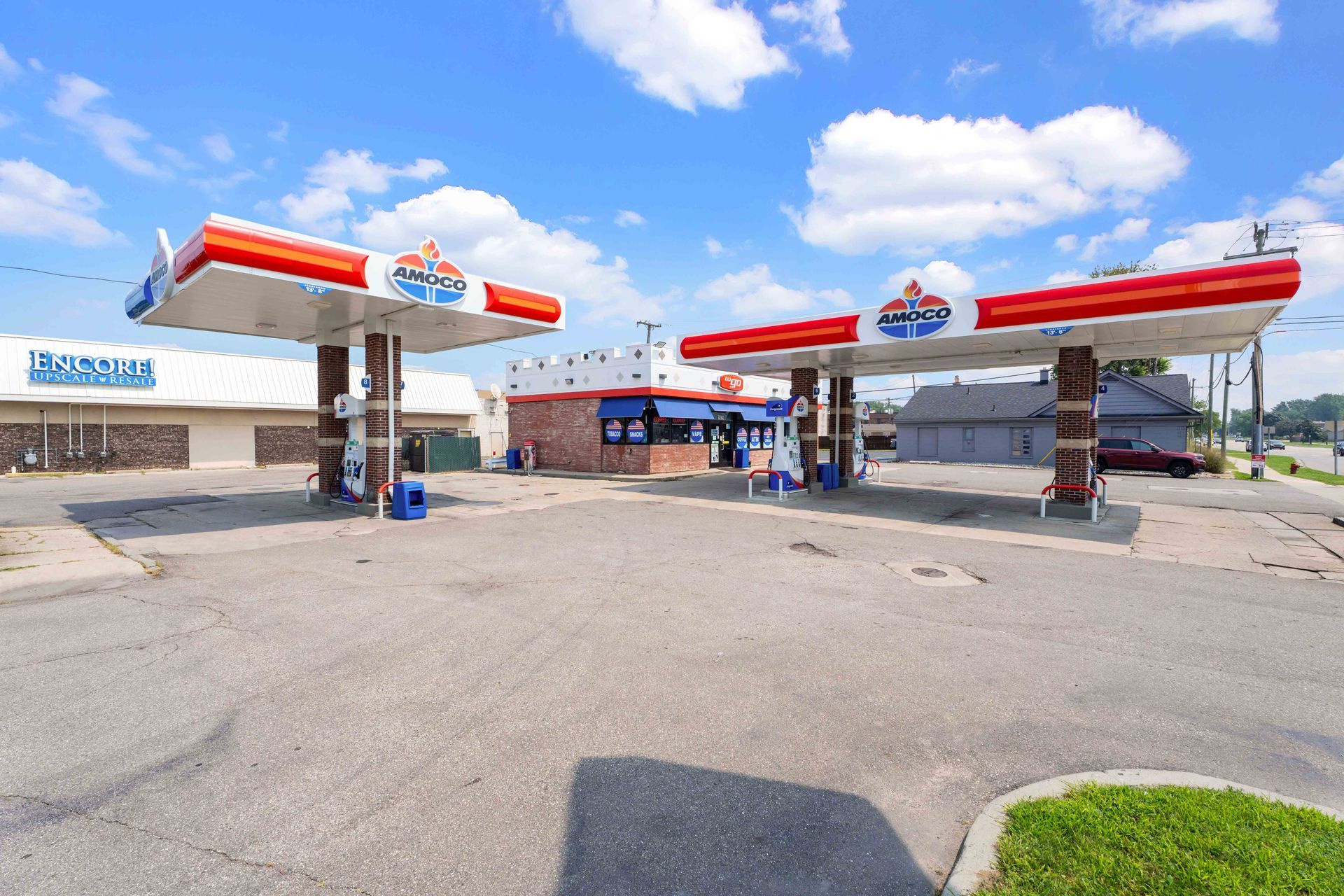 Gas station with red and white canopies, blue sky.