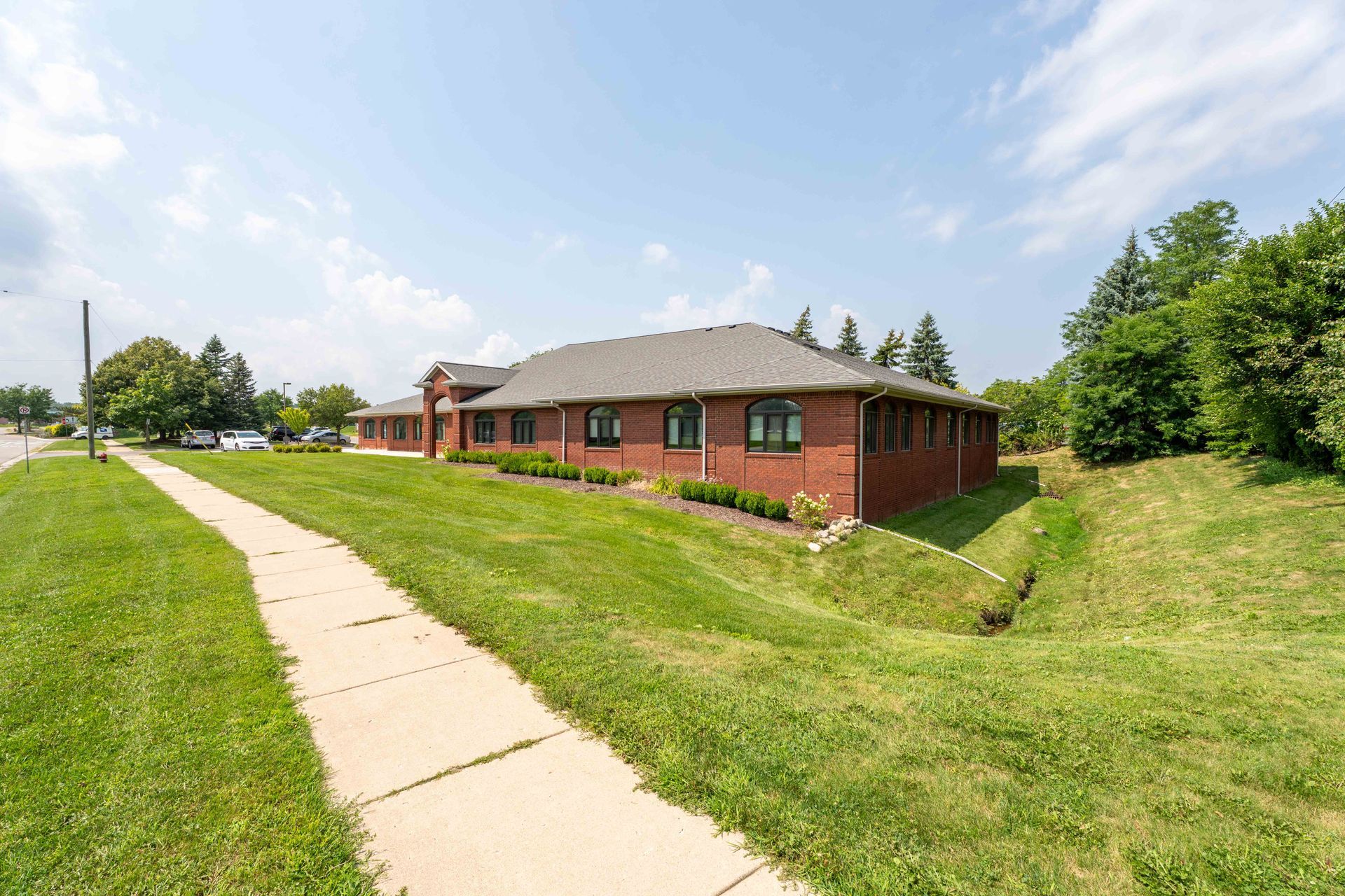 Brick building with a sidewalk and grass. Bright sunny day.