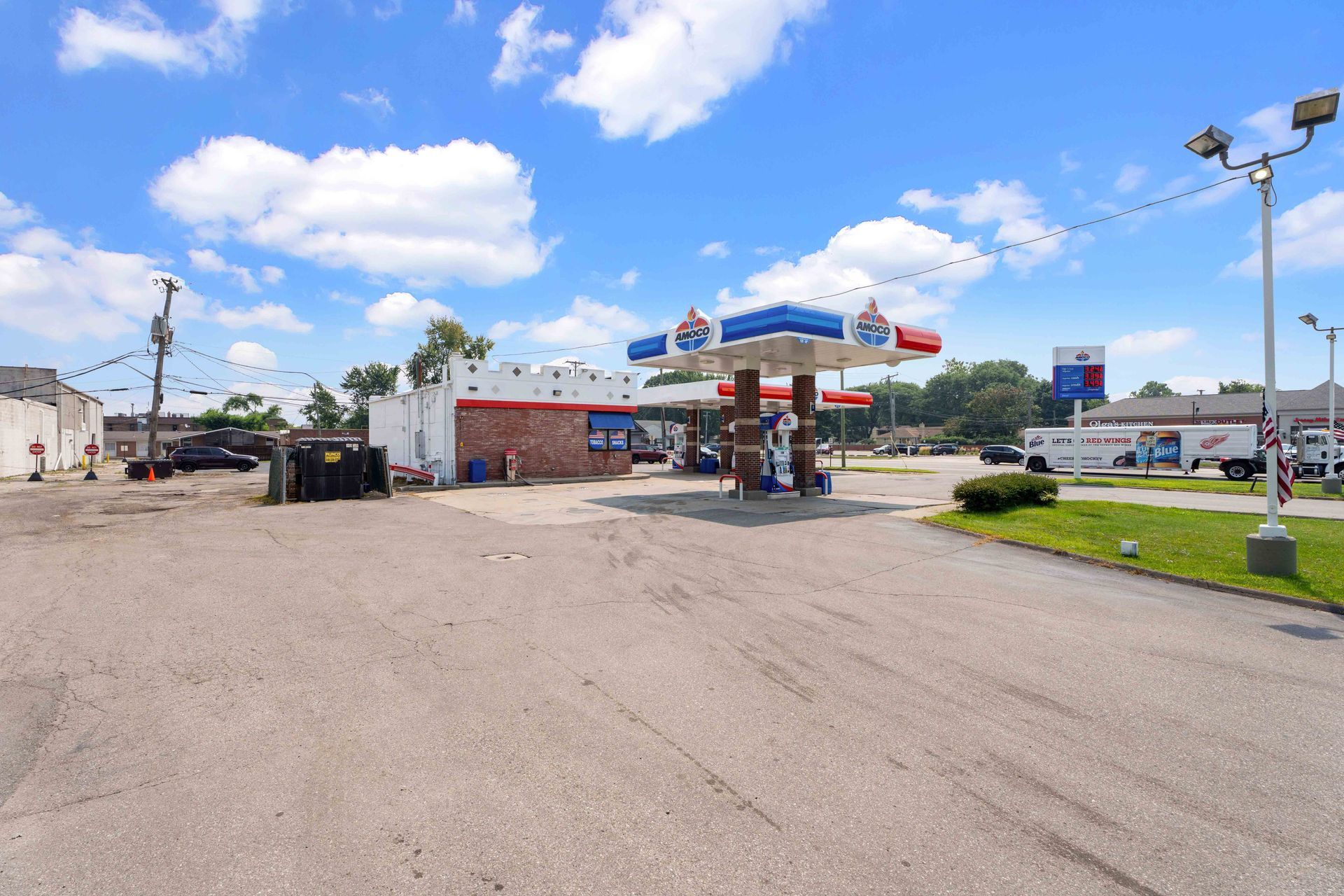 Gas station with blue and red canopy under a bright blue sky.