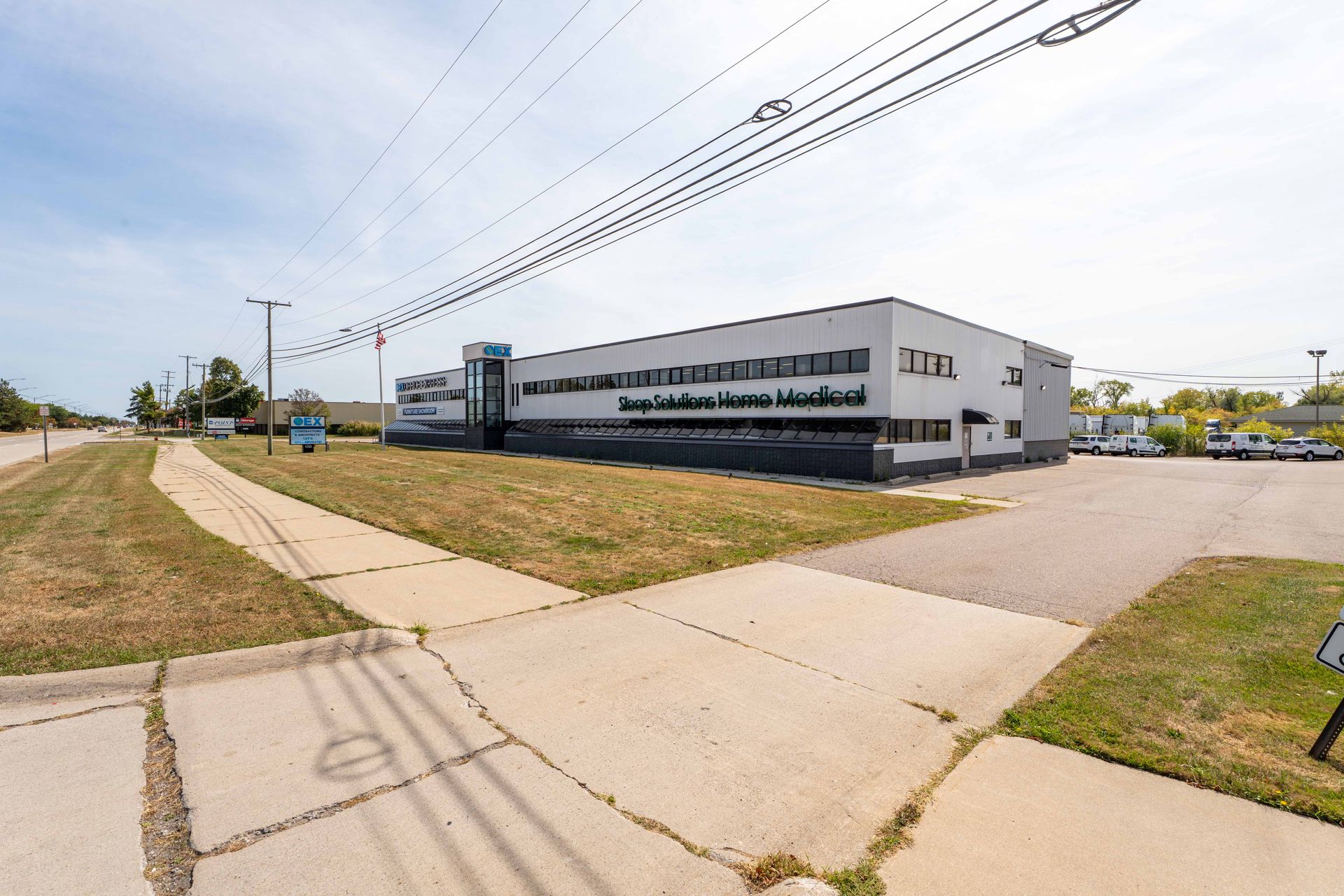 A two-story white building with a paved parking lot on a sunny day.
