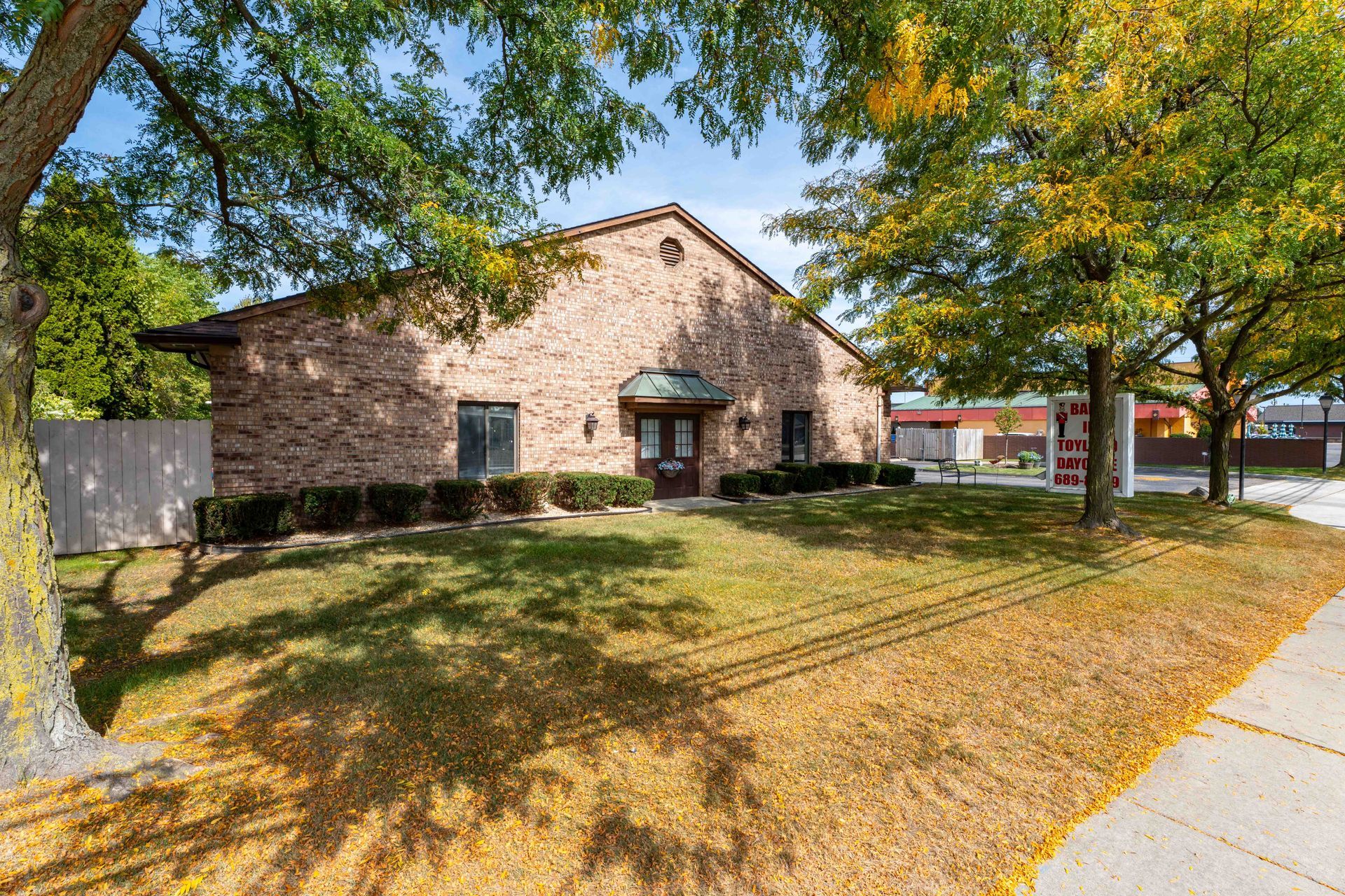 Brick building with arched doorway and trees on a grassy lawn.