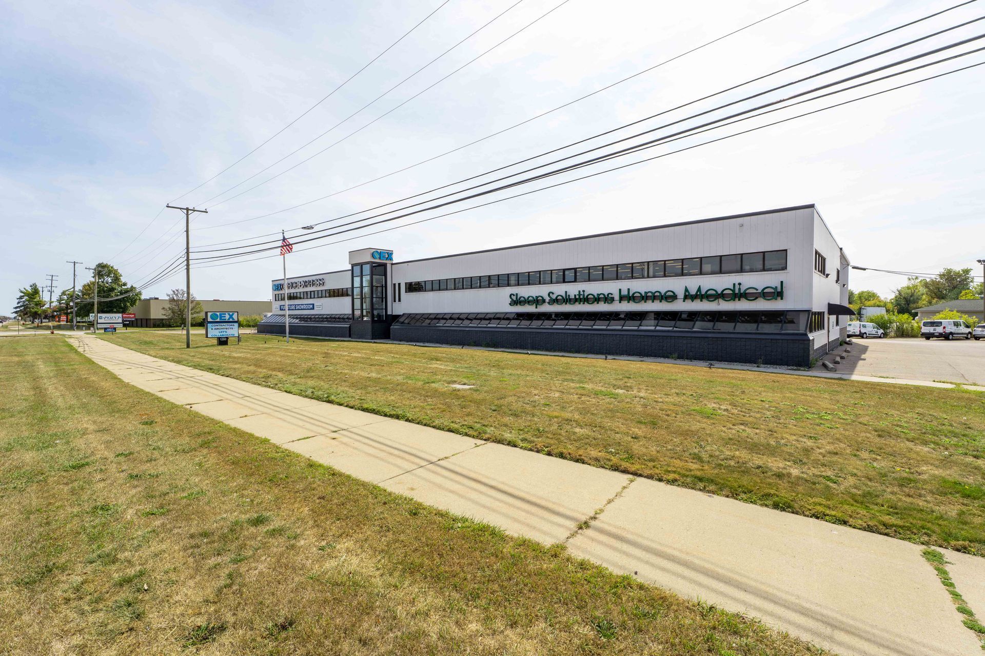 Exterior of a two-story medical supply building; sidewalk and grass in foreground. Blue sky.