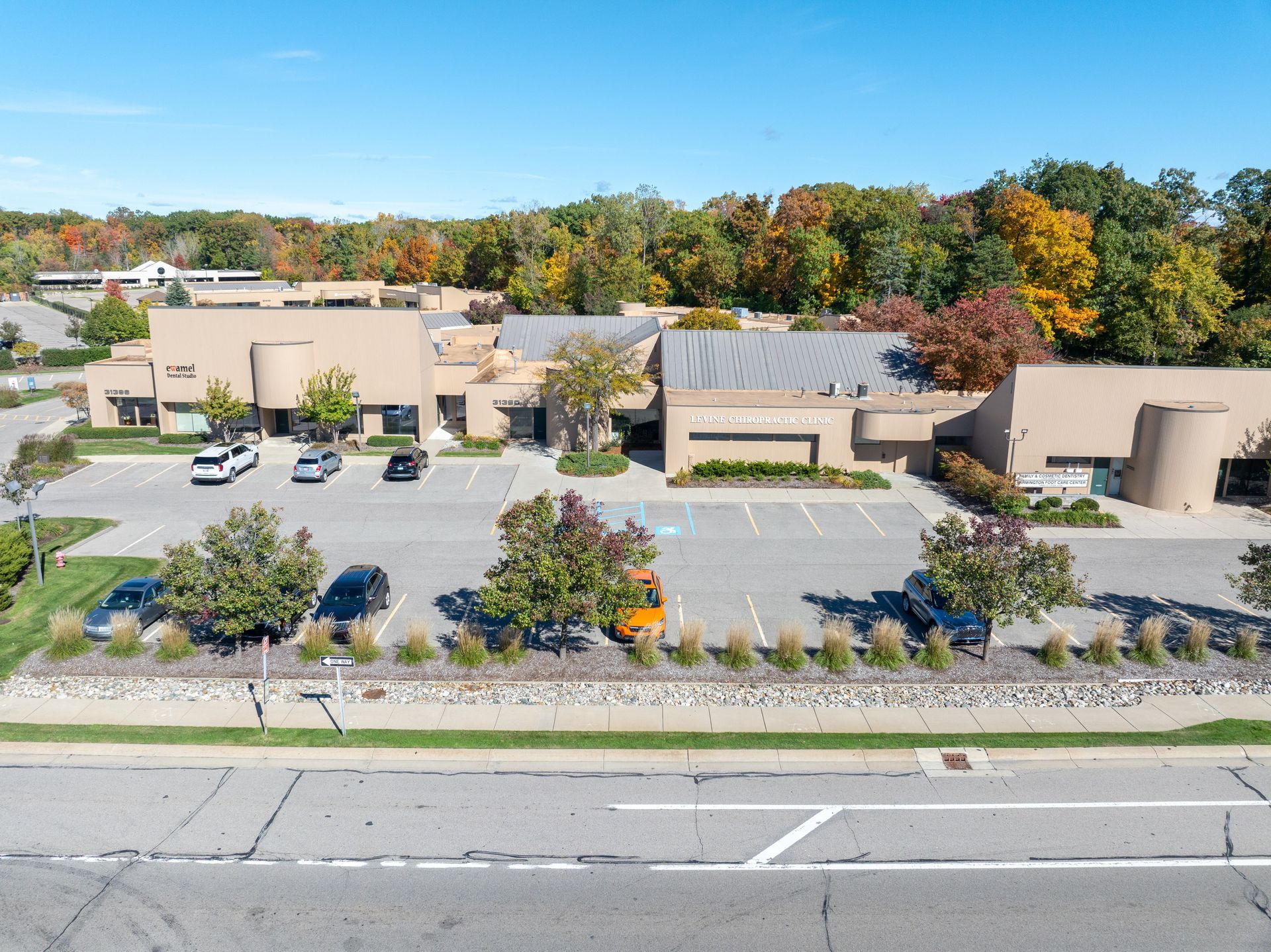 Buildings with parking in front on a bright, sunny day with colorful fall foliage.
