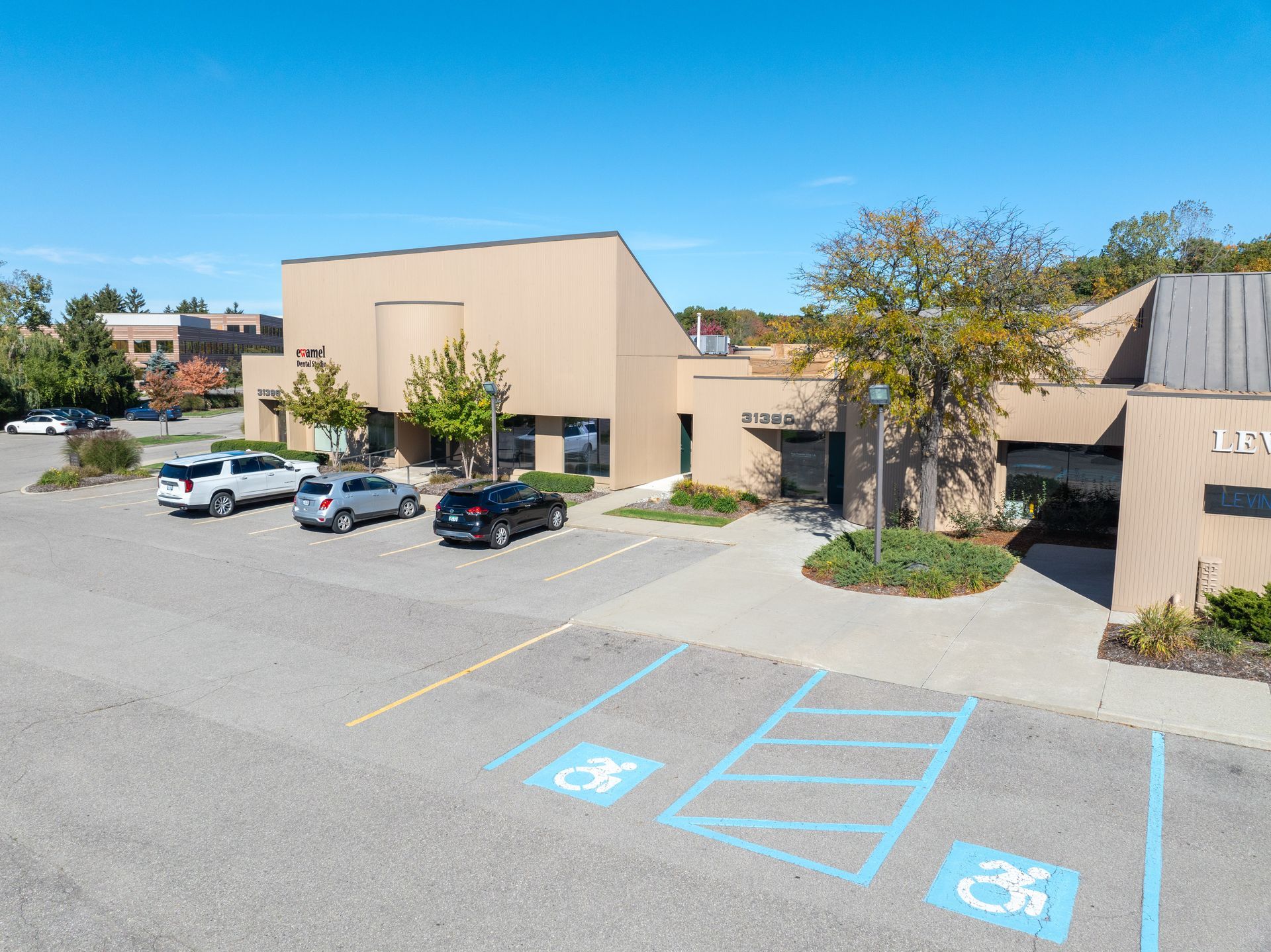 Exterior view of a tan commercial building with a parking lot, including accessible parking spaces.
