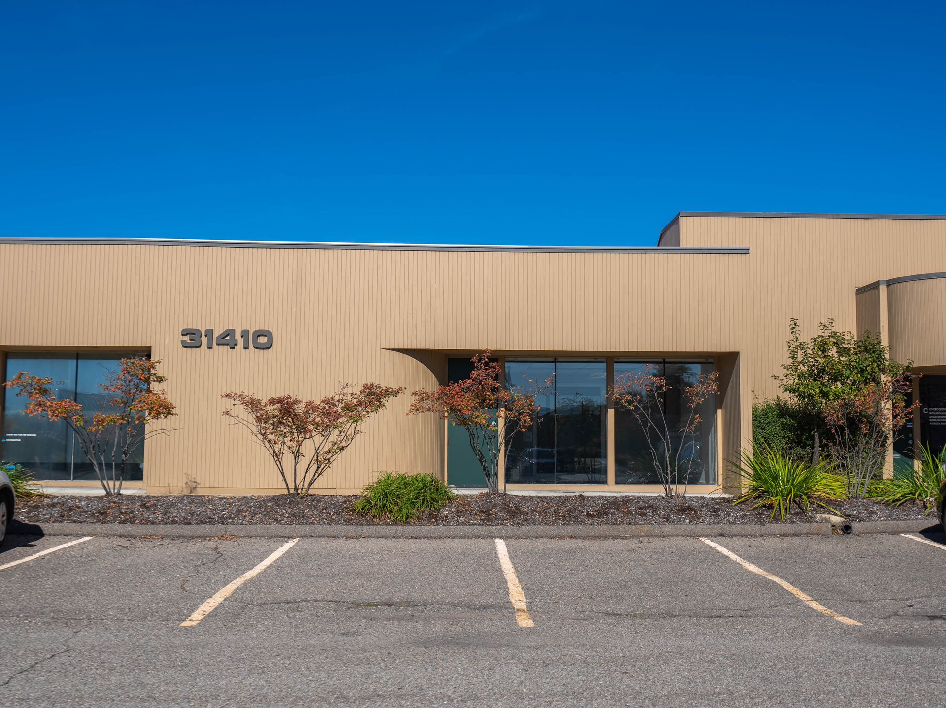 Beige office building with parking lot and blue sky; address 31410.
