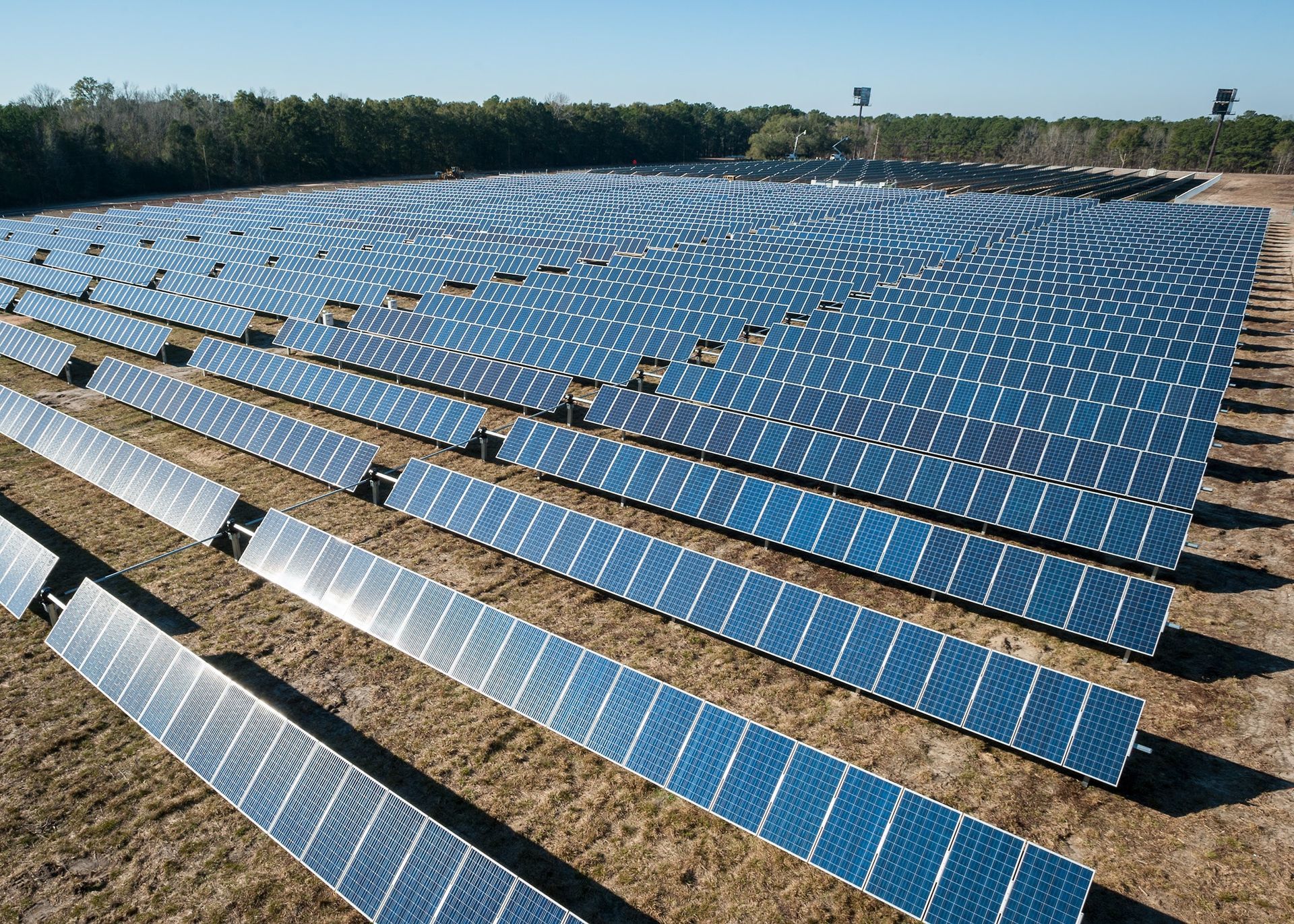Large solar panel array in a field, generating renewable energy. Blue panels, sunny day.