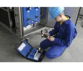 A man is kneeling on the floor working on a machine.