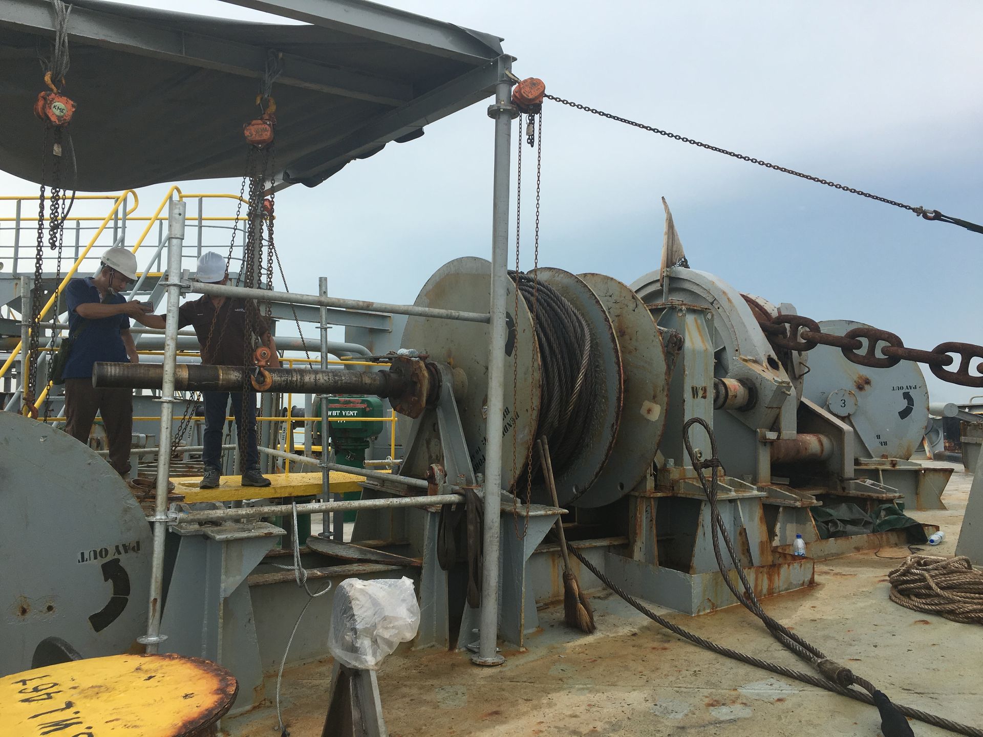 Mooring Winch Installation onboard a marine vessel with 2 engineers wearing safety helmet survey the damaged area