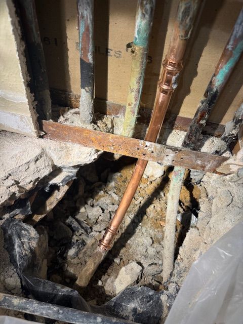 A copper pipe is sticking out of a hole in the wall