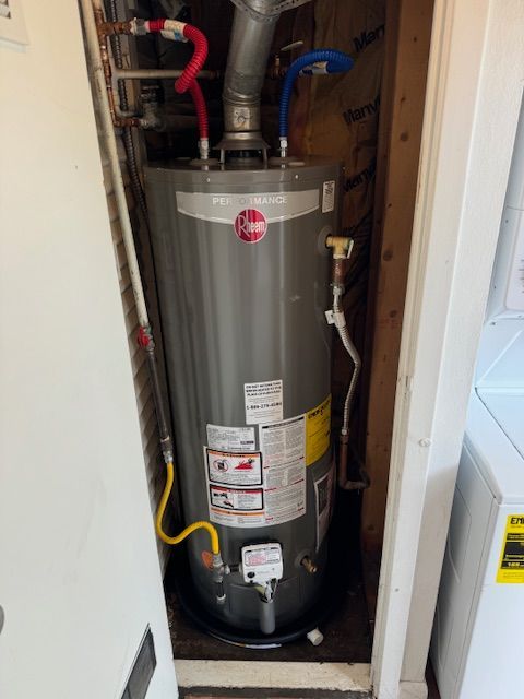 A water heater is sitting in a closet next to a door