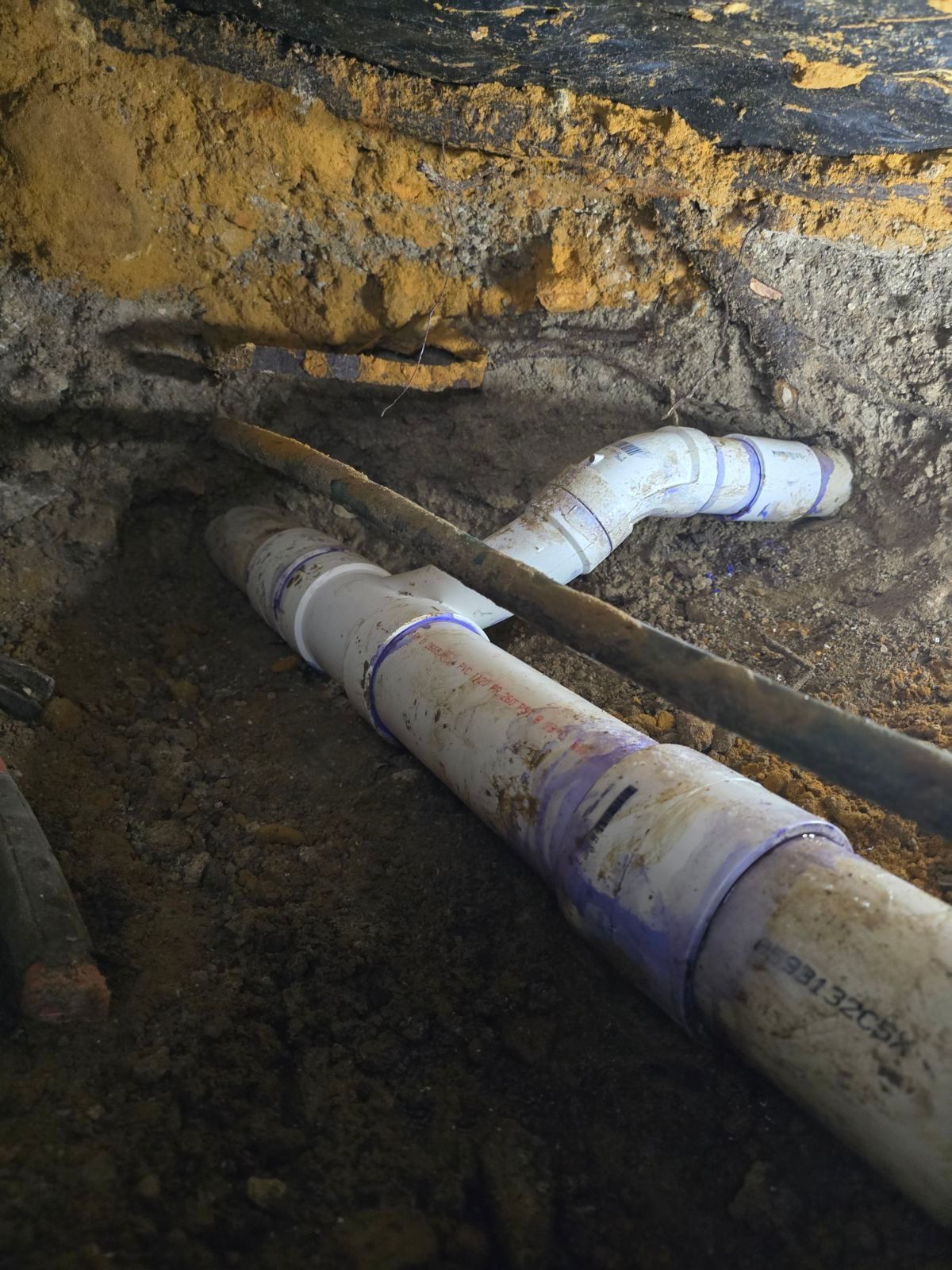 A bunch of pipes are laying in the dirt