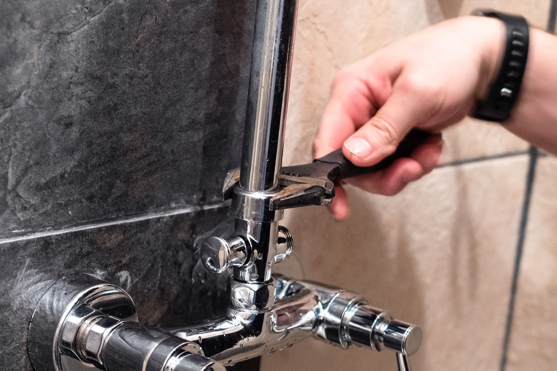 A person is fixing a faucet with a pair of pliers