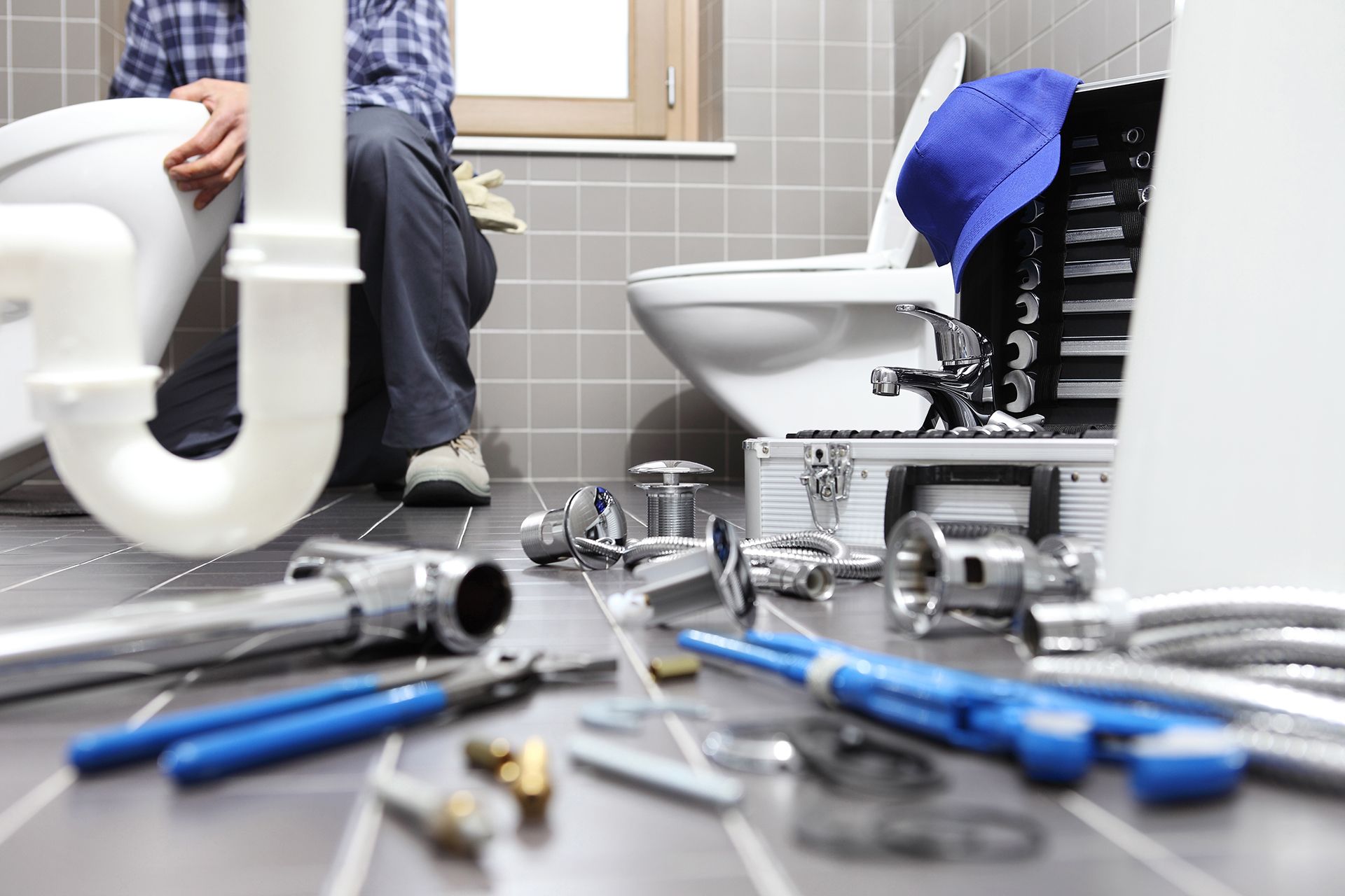 A plumber is fixing a toilet in a bathroom
