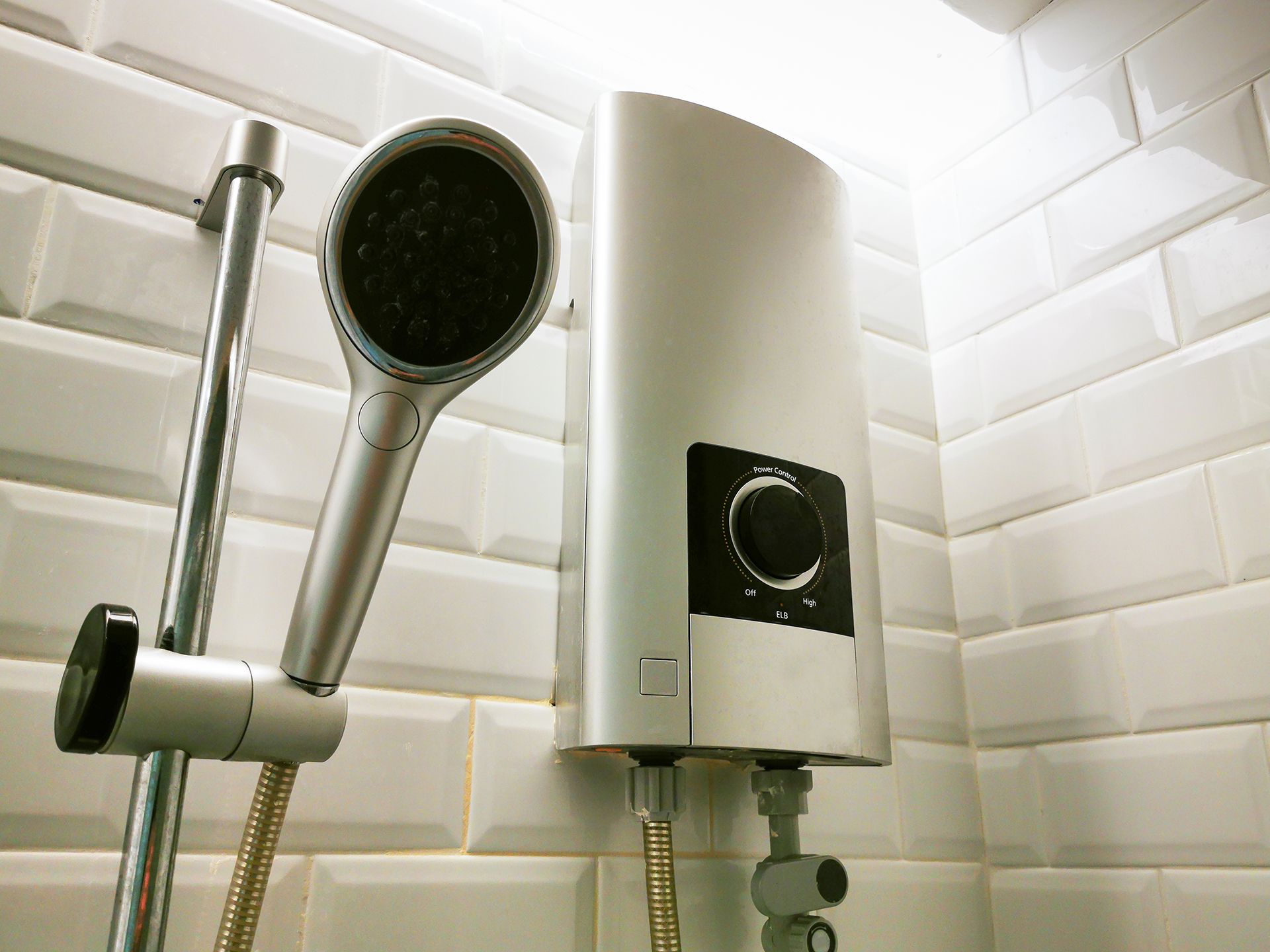 A shower head is attached to a water heater in a bathroom