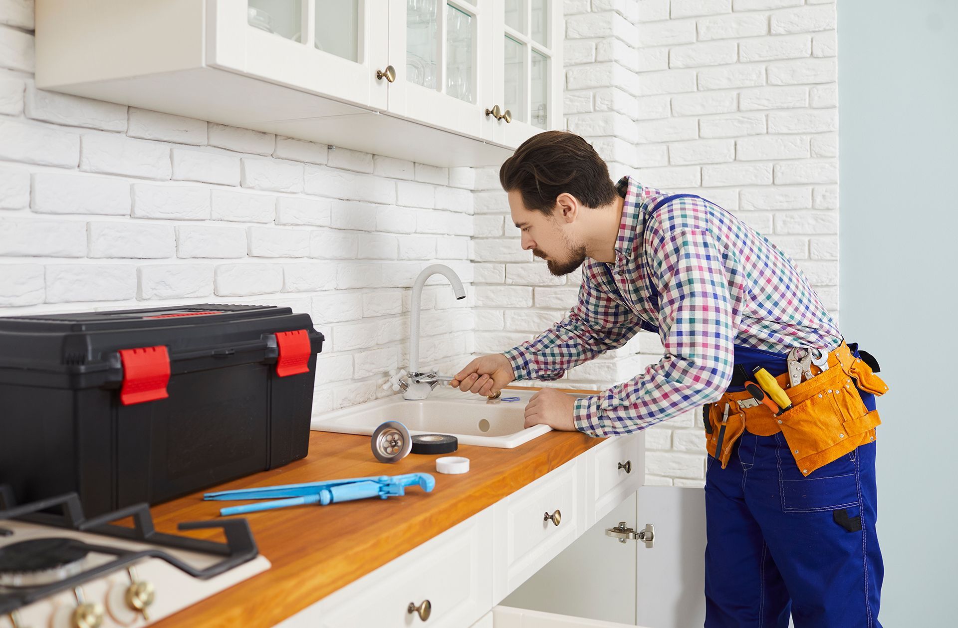 A man is fixing a sink in a kitchen