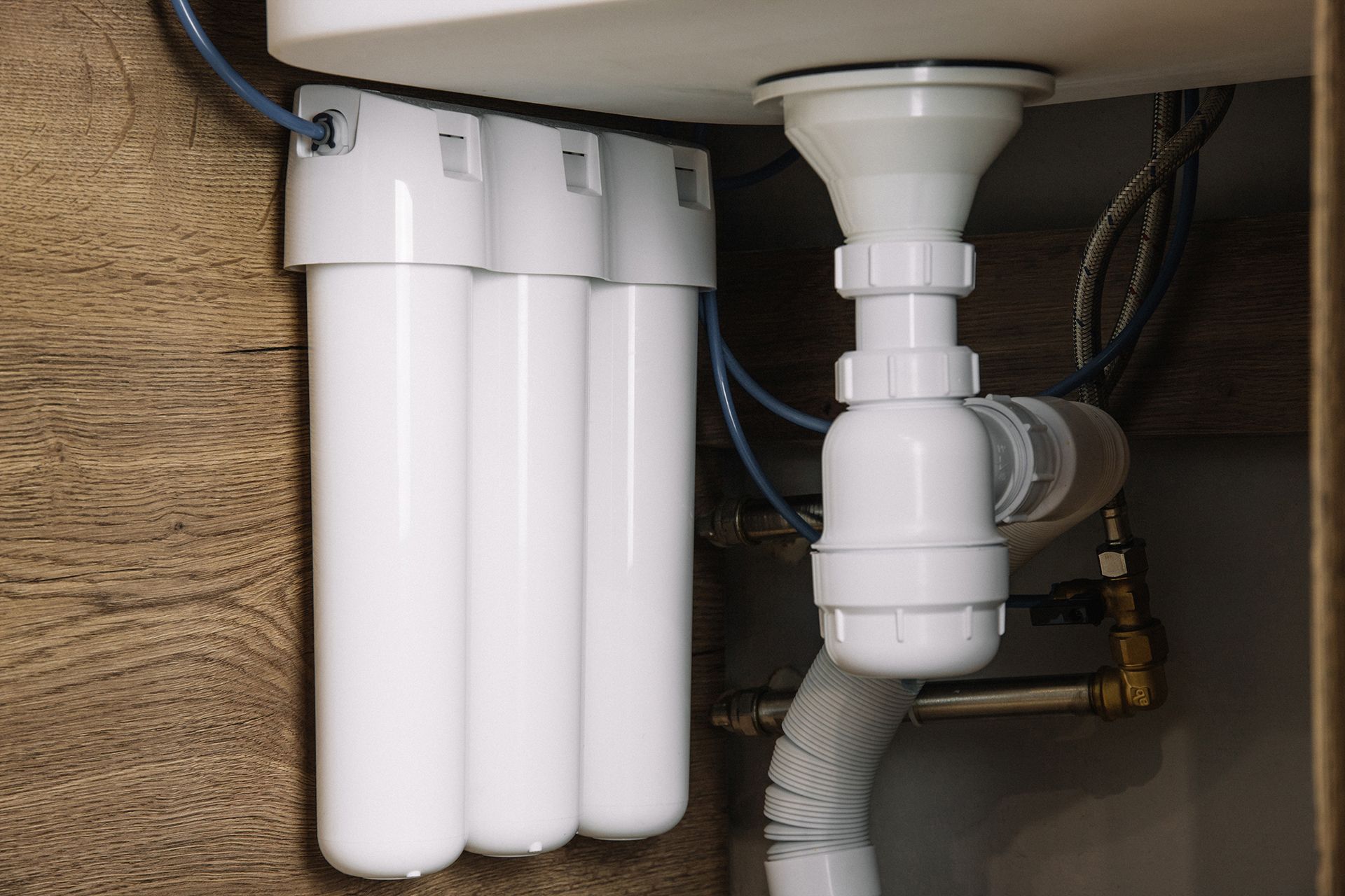 A water filter is installed under a sink in a kitchen