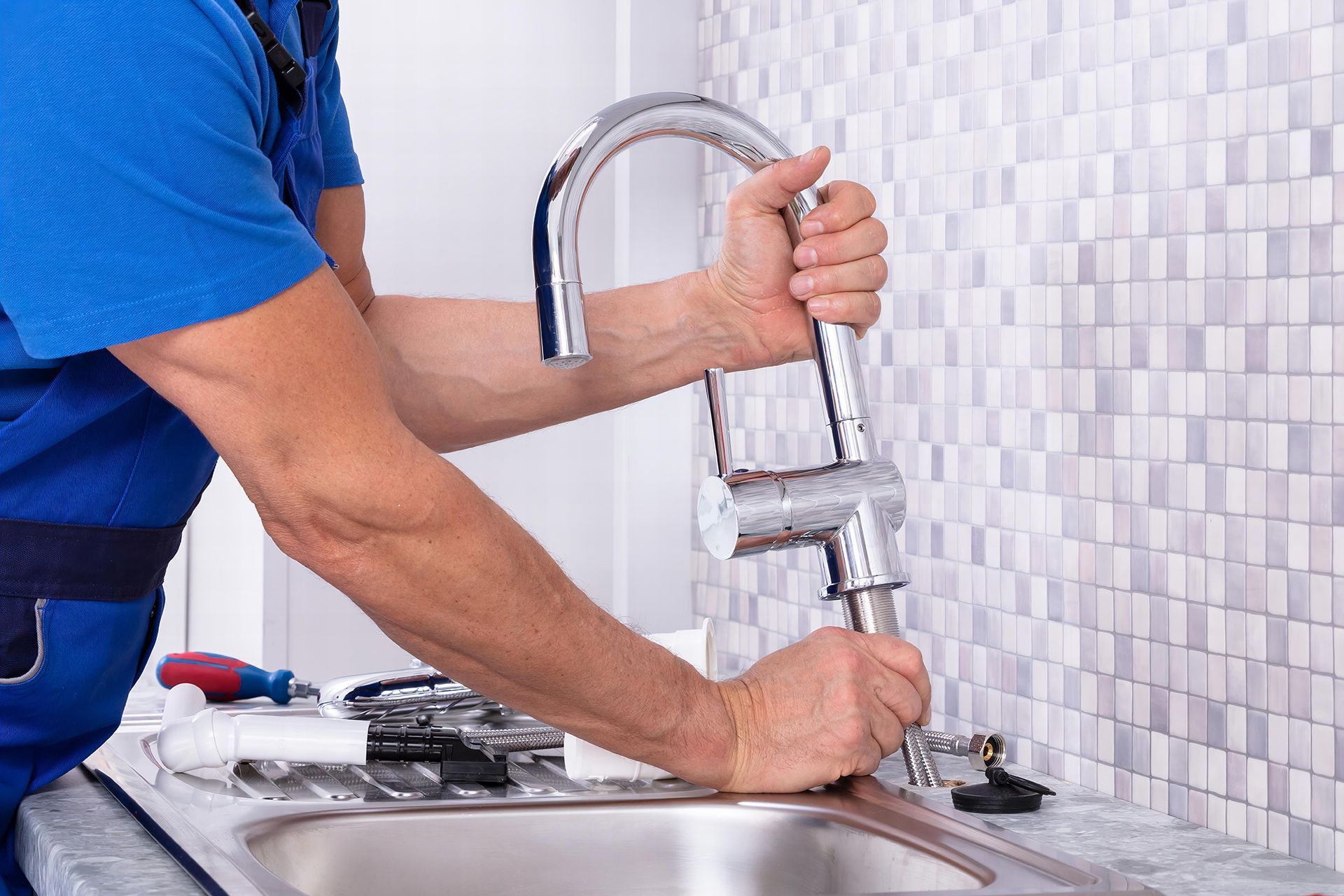A man is fixing a faucet in a kitchen sink