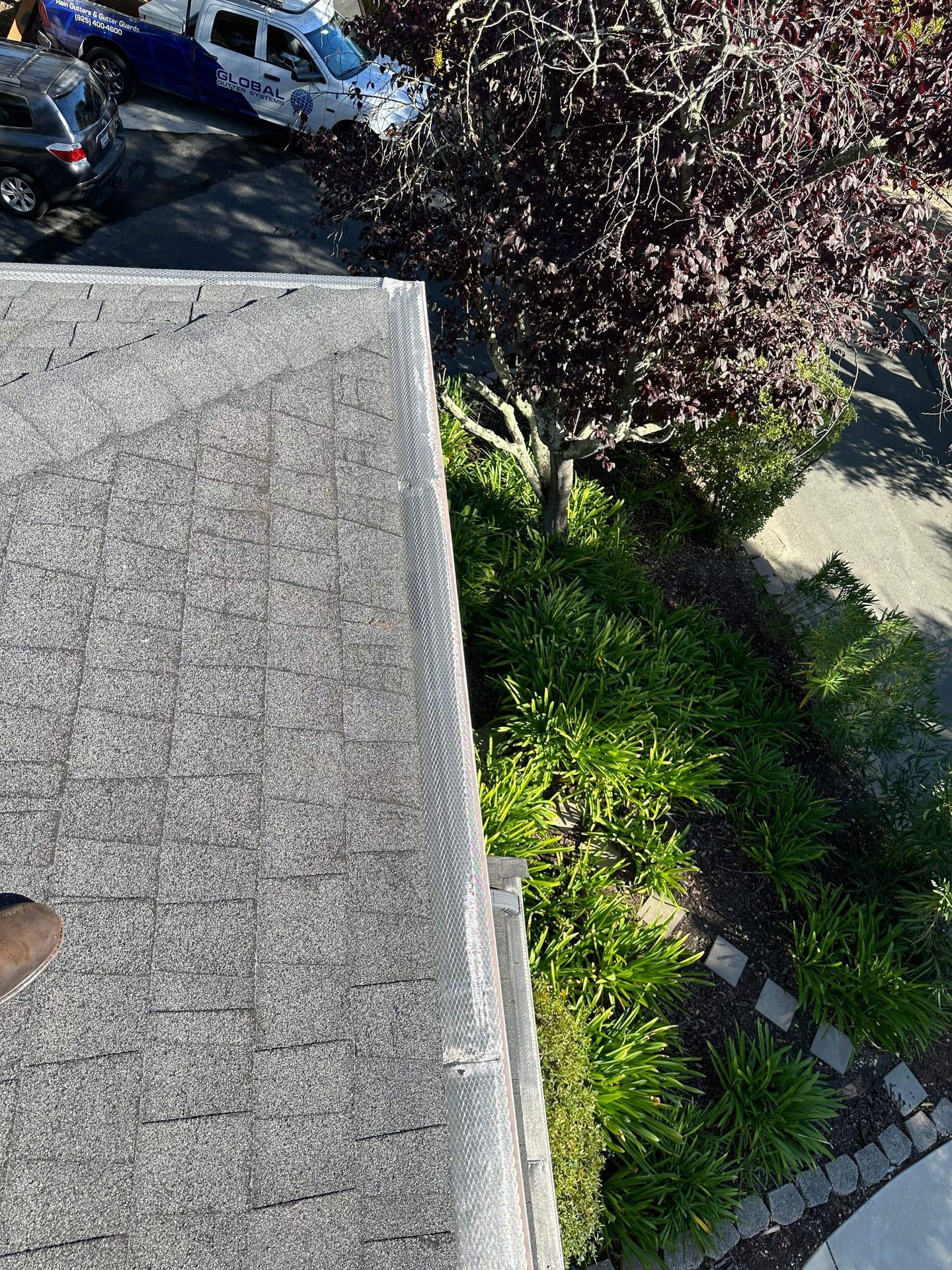 An aerial view of a roof with a gutter and trees in the background.