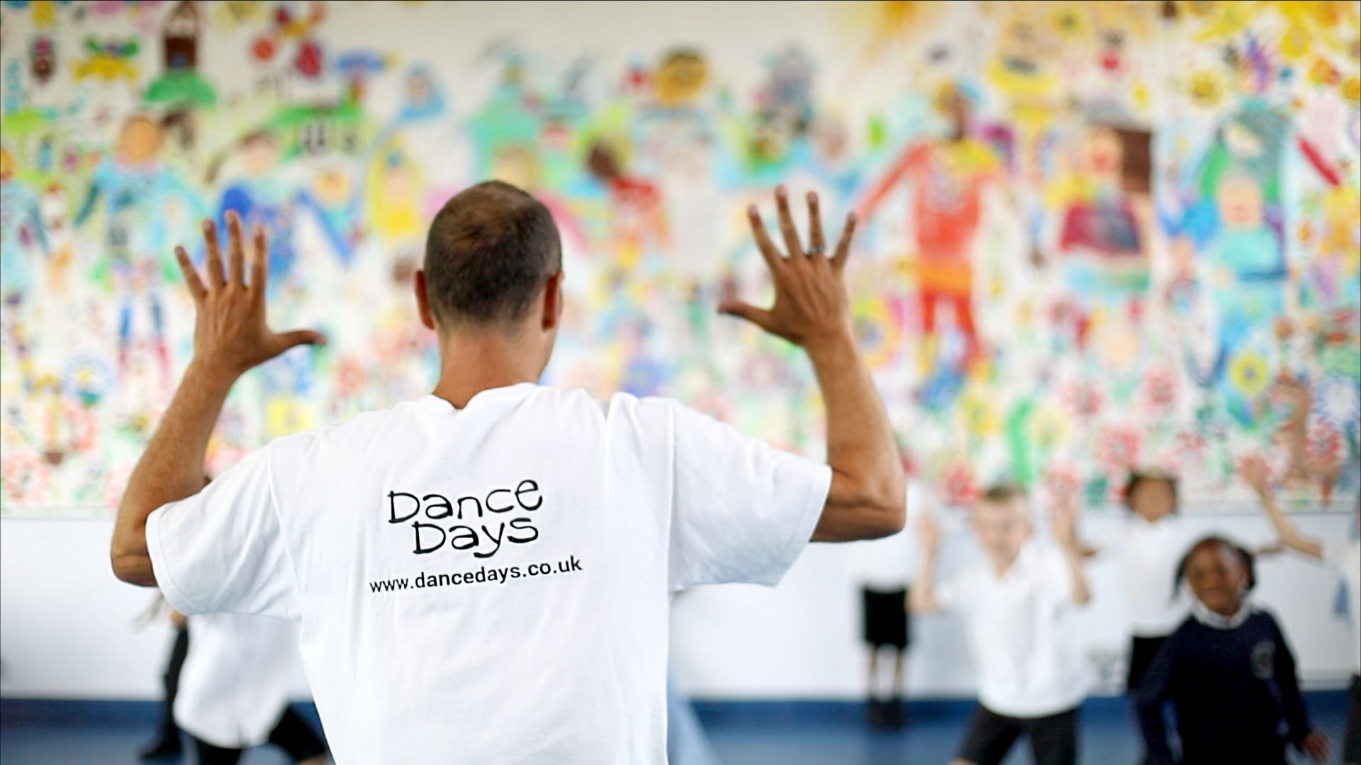 A dance days instructor is standing in front of a group of children.