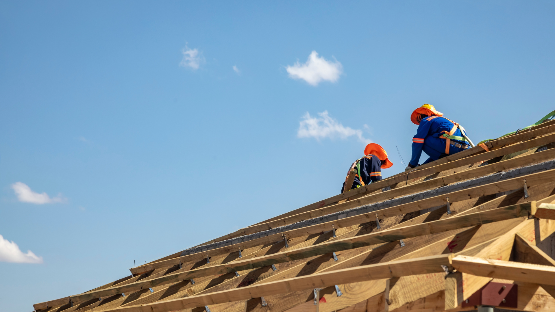 Two construction workers are working on the roof of a building.