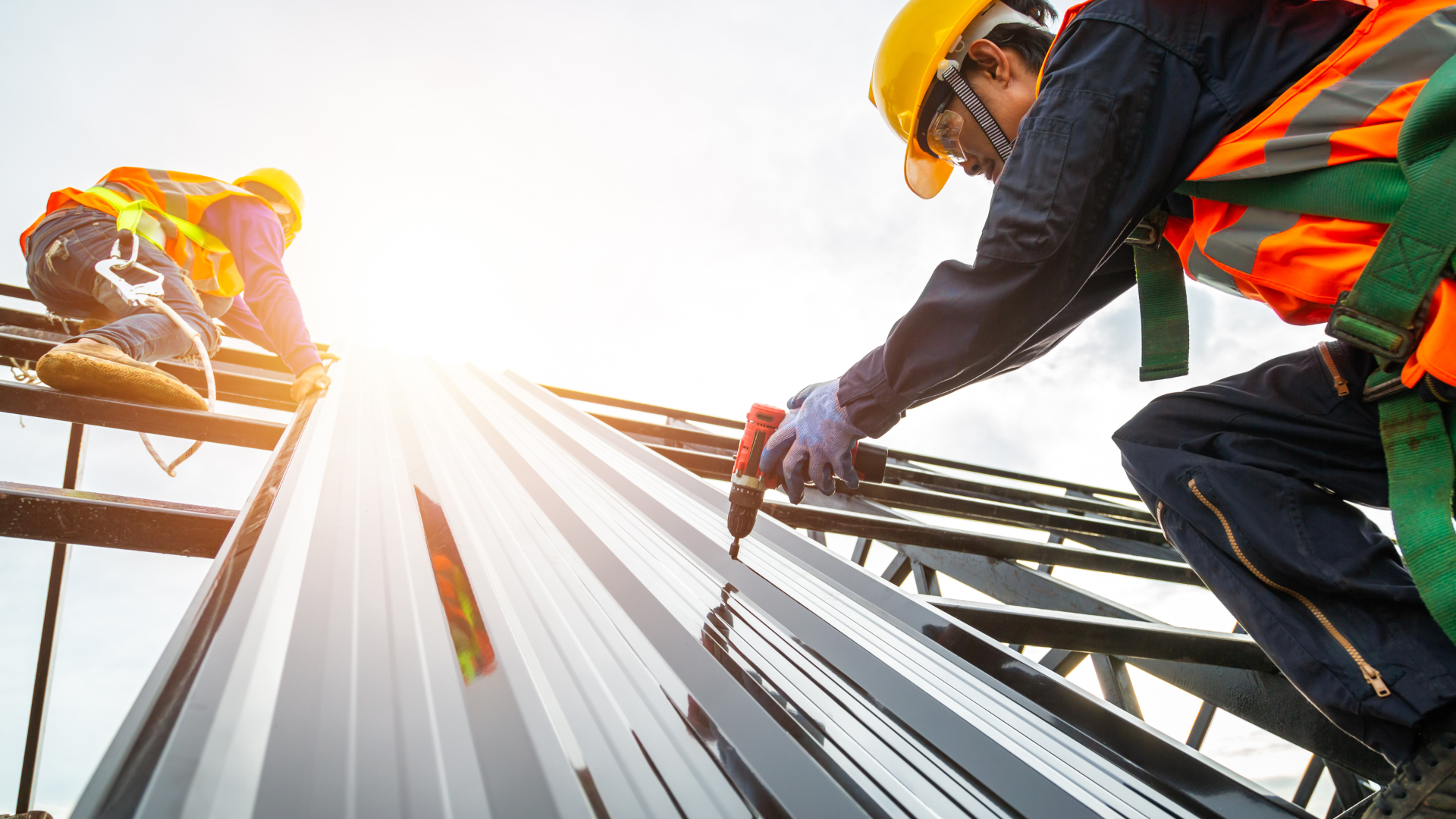 Two construction workers are working on the roof of a building.