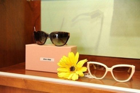 a pair of sunglasses sitting on top of a pink box next to a yellow flower .