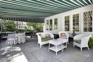 A patio with white furniture and a green and white striped awning.