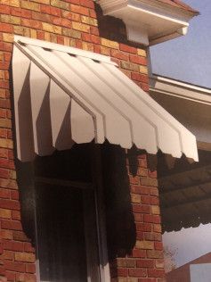 A white awning is on the side of a brick building.