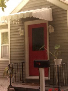 A small house with a red door and a mailbox.