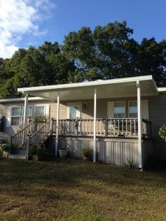 A mobile home with a porch and stairs on a sunny day.