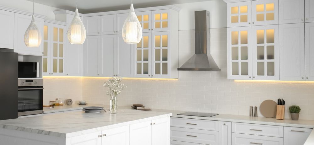 A kitchen with white cabinets and a marble counter top.