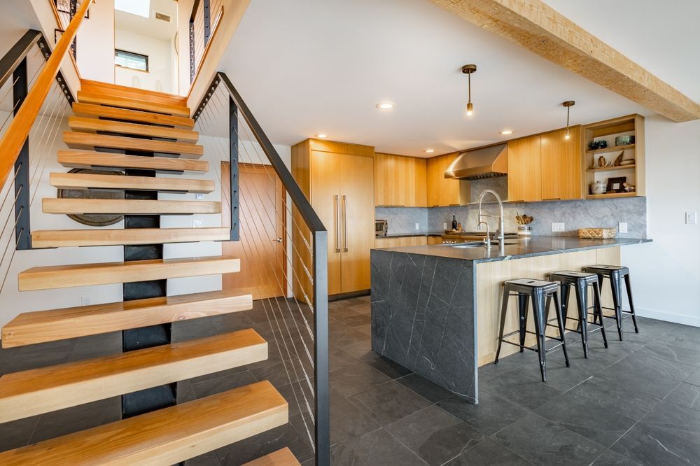 A kitchen with a wooden staircase leading up to the second floor.