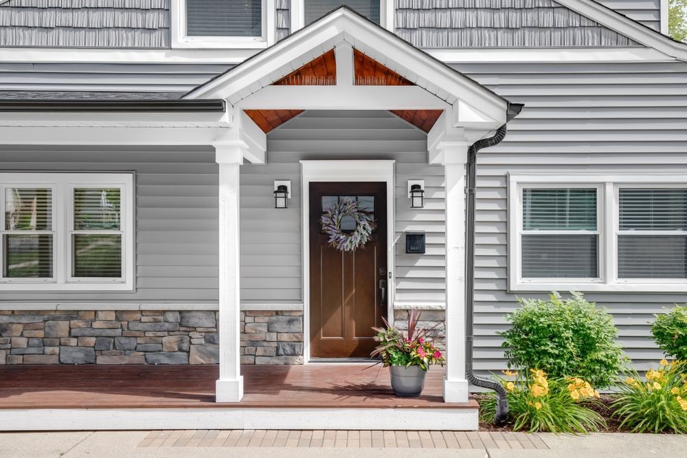 The front of a house with a porch and a brown door.