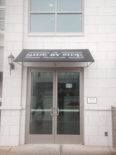 A white building with a black awning over the door.