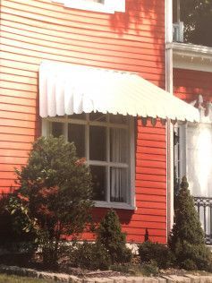 A red house with a white awning over a window.