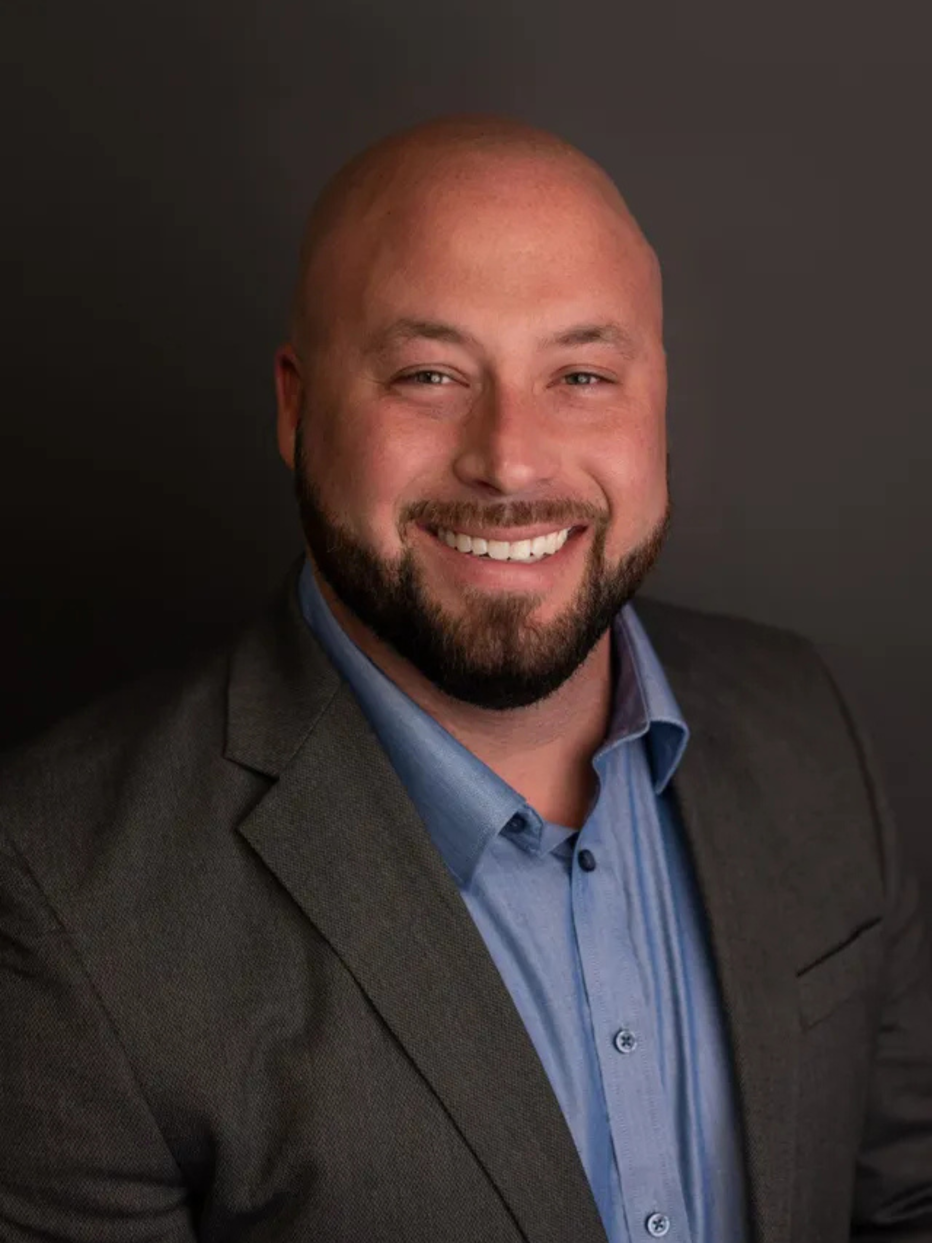 Jade Purdy wearing glasses and a white shirt is smiling in front of a painting.