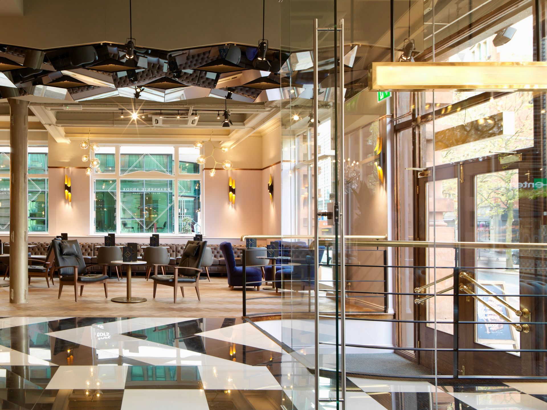 Stylish hotel lobby with geometric floor, glass door, seating areas.