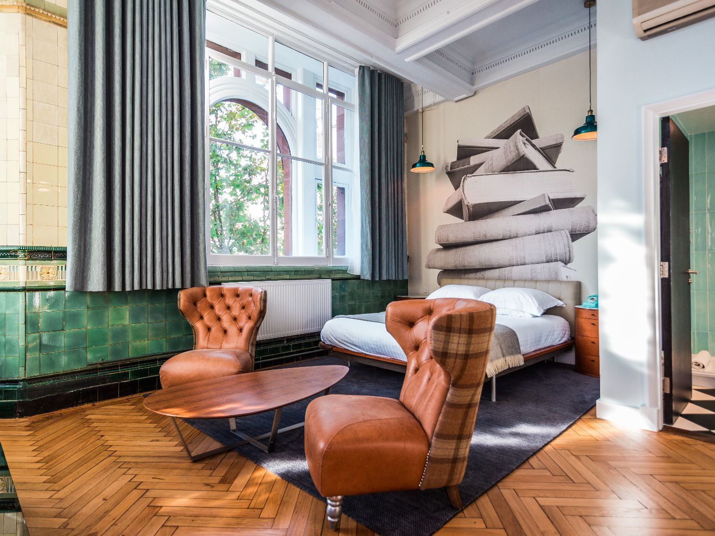 Bedroom with brown leather chairs, double bed, and green tile wall.