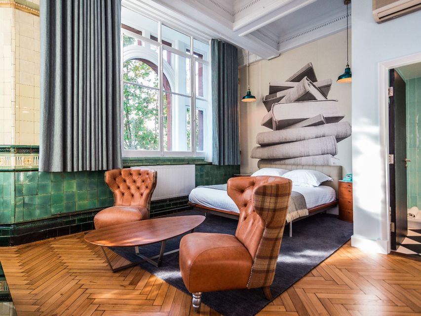 Bedroom with brown leather chairs, double bed, and green tile wall.