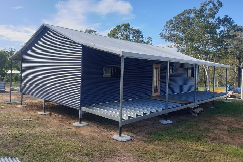 A Small House with A Porch Is Sitting on Top of A Lush Green Field — All Steel Homes in Branyan, QLD