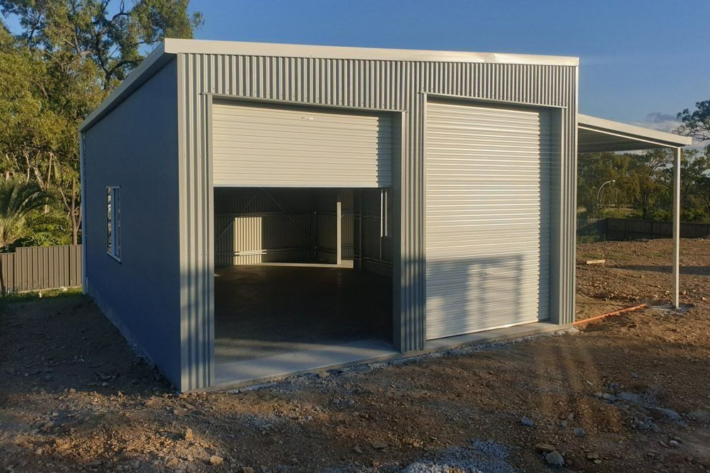A Garage with Two Garage Doors and A Canopy Is Being Built in A Dirt Field — All Steel Homes in Branyan, QLD