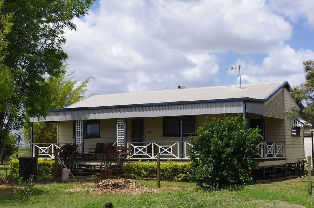 A Small White House with A Porch and Trees in Front of It — All Steel Homes in Maryborough, QLD