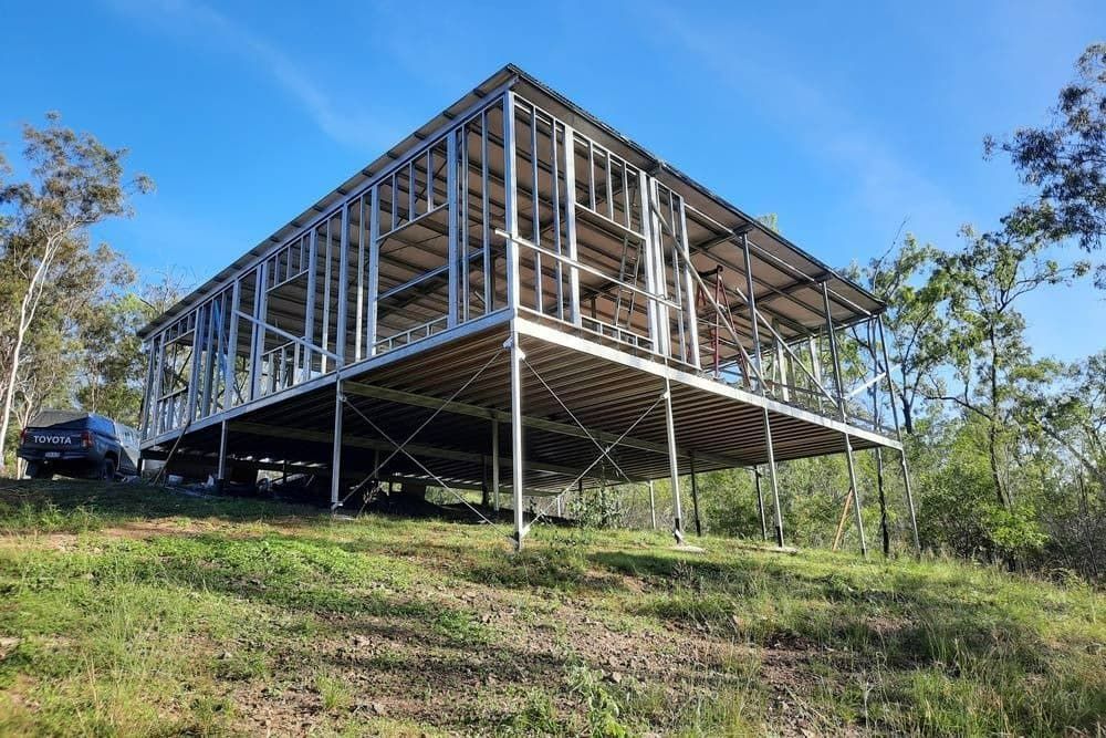 A House Is Being Built on A Hill with A Car Parked in Front of It — All Steel Homes in Childers, QLD