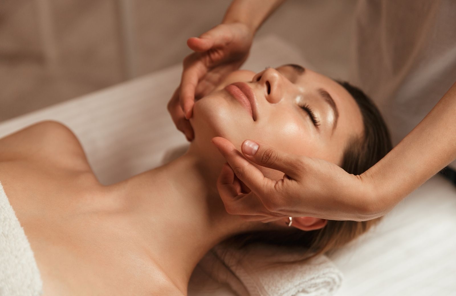 A woman is getting a facial massage at a spa.