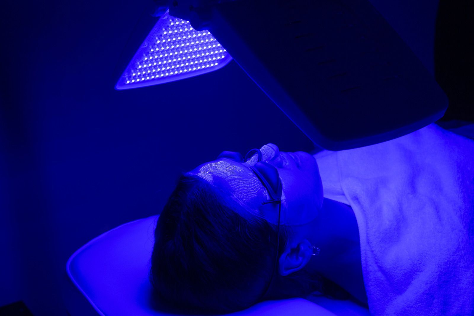 A woman is laying on a bed under a blue light.