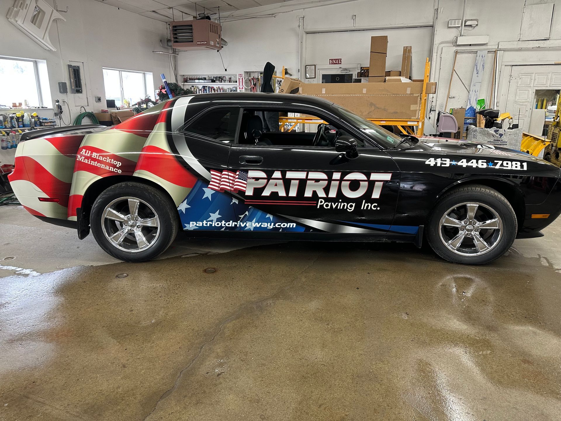 A black car with patriotic graphics is parked in a garage.