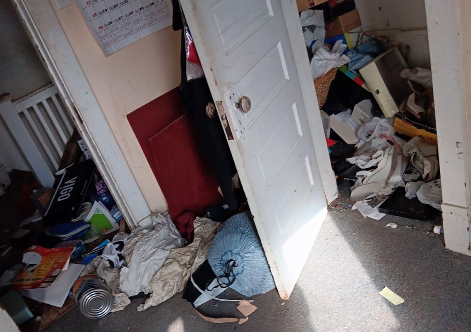 A room filled with trash and junk in bags, blocking the door from opening fully