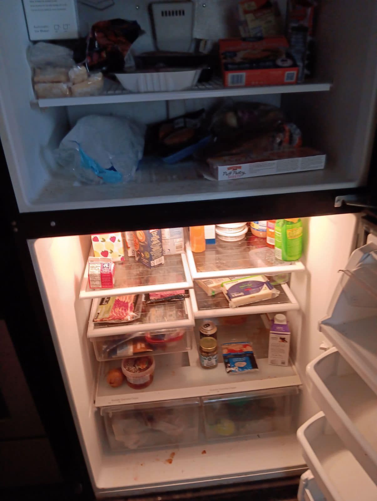 a cluttered dirty refrigerator with groceries